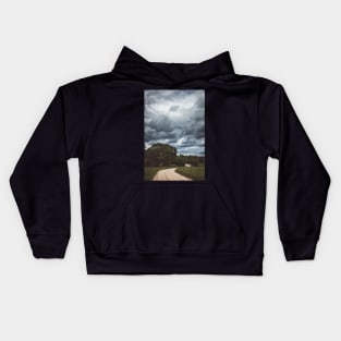 Country road under dark cloudy sky Kids Hoodie